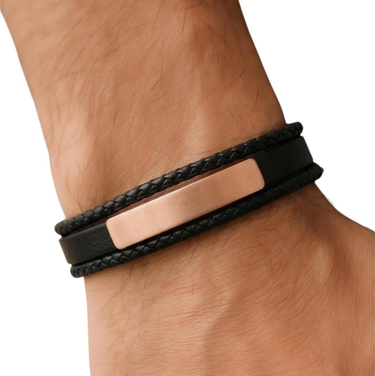 Black braided leather bracelet with a rose gold tag on a wrist against a white background
