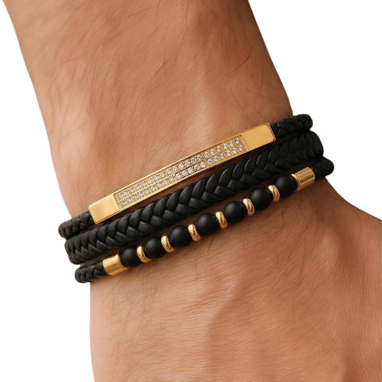 Black braided bracelet with gold accents on a wrist against a white background