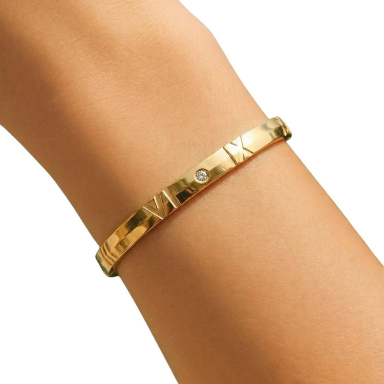 Gold bracelet with a diamond on a wrist against a white background