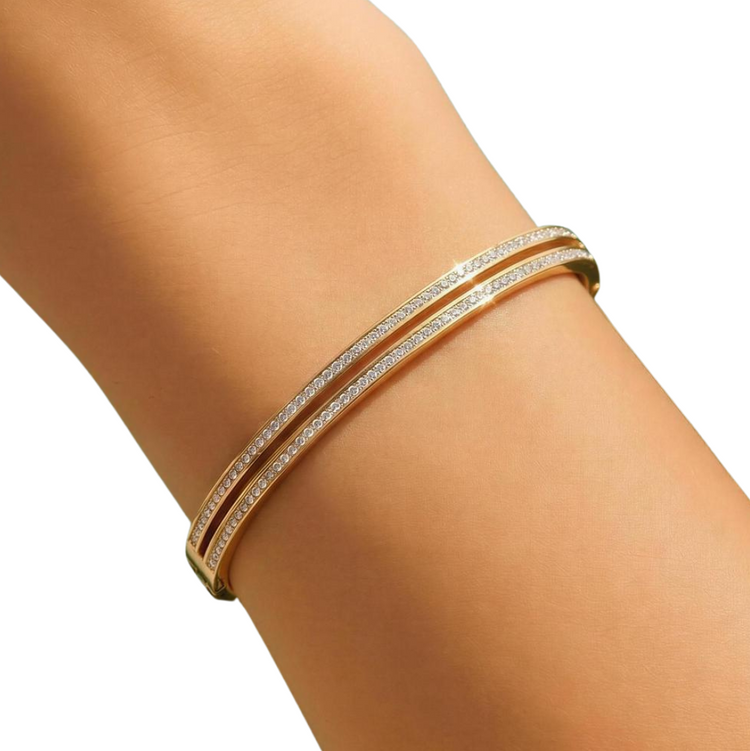 Gold bracelet on a person's wrist with a plain background
