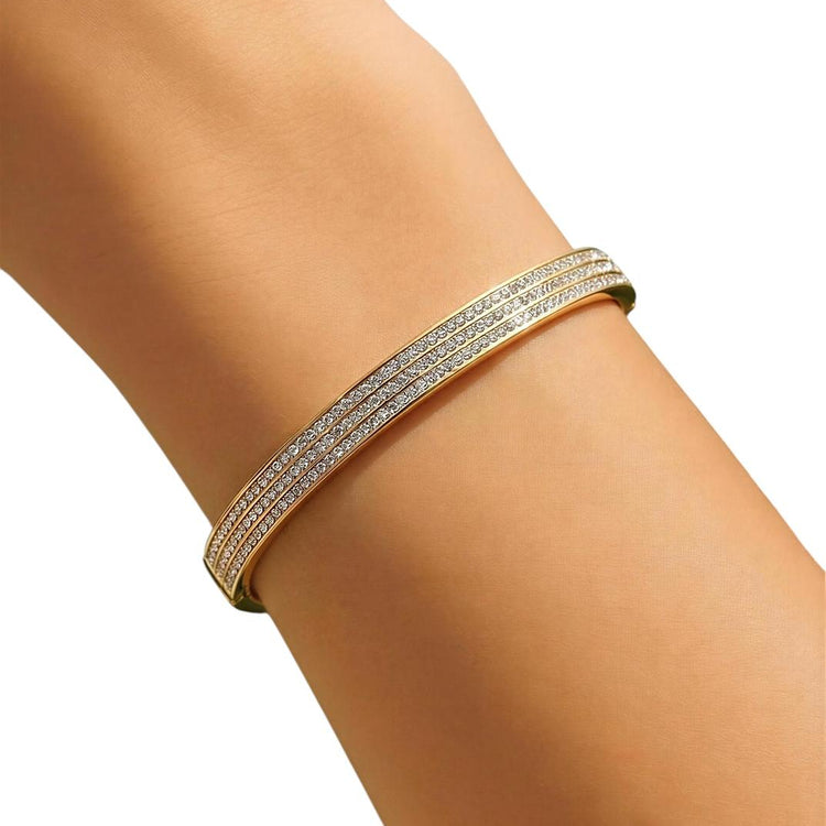 Gold bracelet on a person's wrist with a plain background