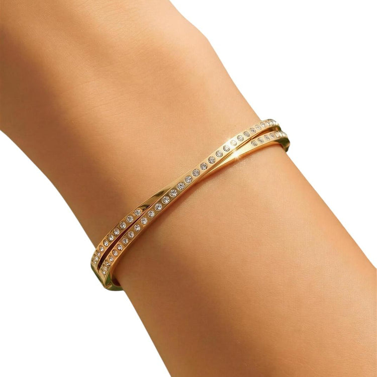 Gold bracelet with clear stones on a person's wrist against a white background