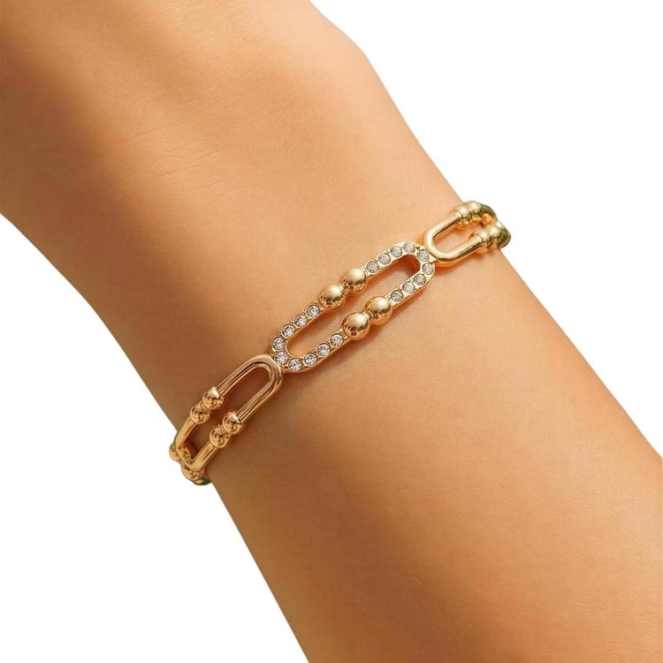 Gold bracelet with clear stones on a wrist against a white background