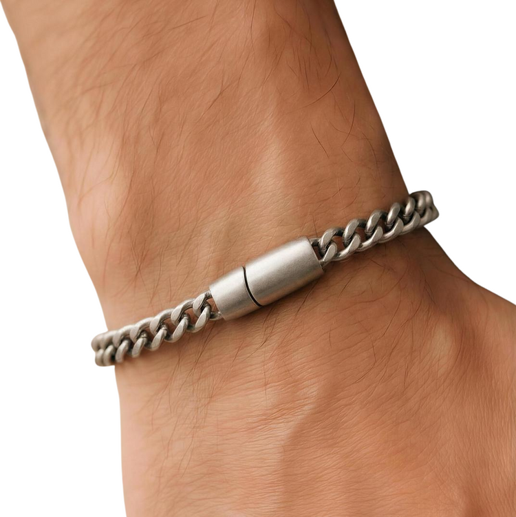 Silver chain bracelet on a wrist with a plain background