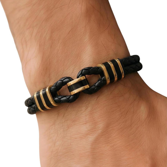 Black and gold braided bracelet on a wrist against a white background