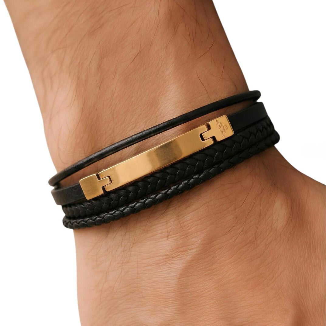 Black leather bracelet with gold clasp on a wrist against a white background