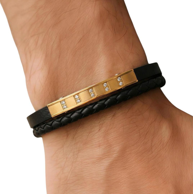 Black leather bracelet with gold accents on a wrist against a white background