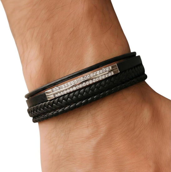 Black leather bracelet with silver bar on wrist against a white background