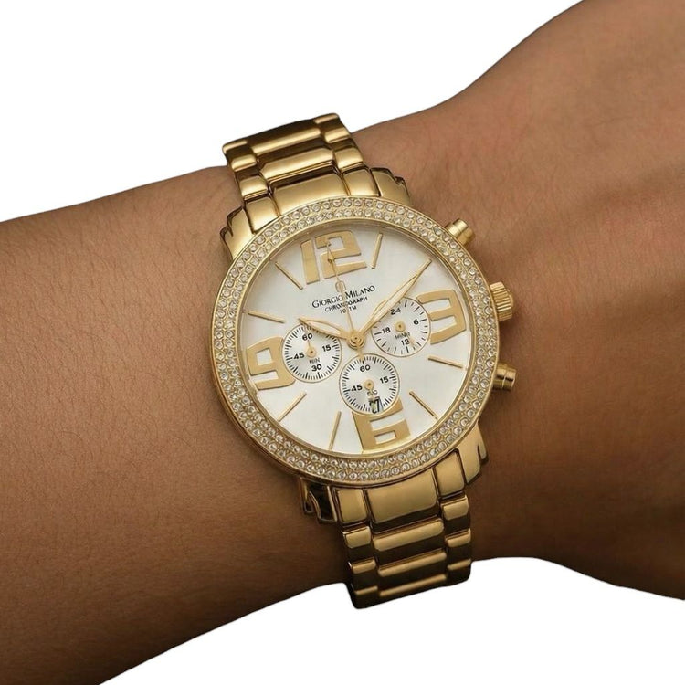 Gold wristwatch with a detailed face on a wrist against a white background