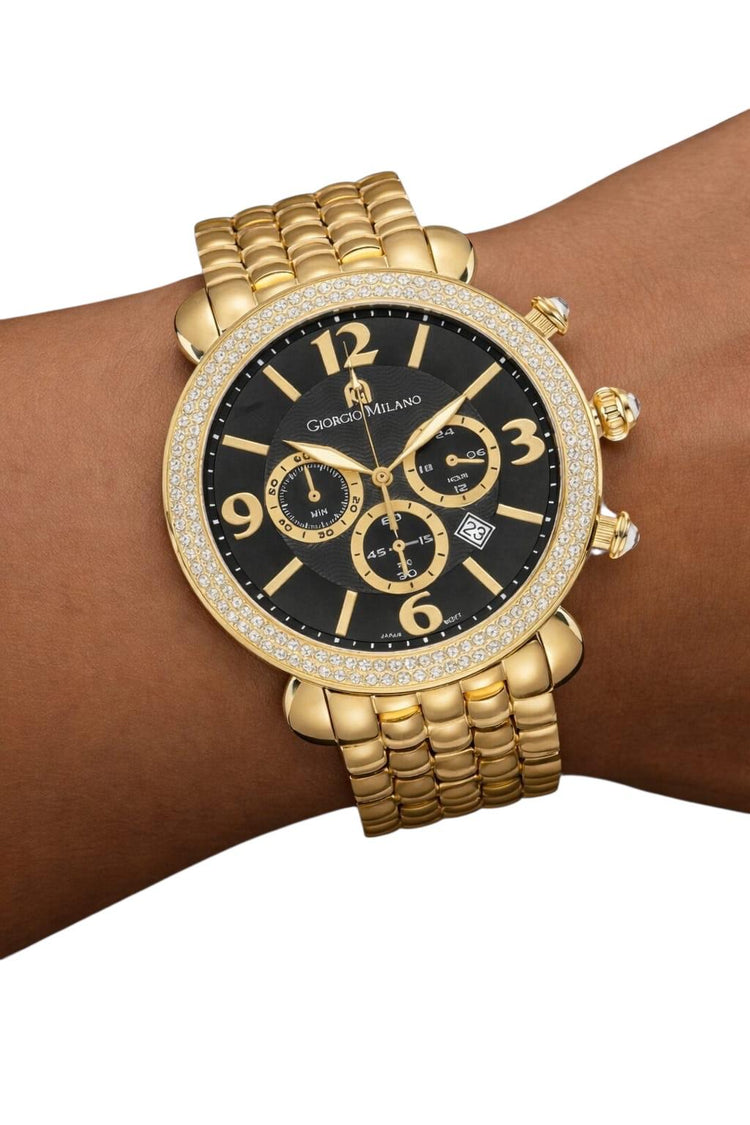 Gold wristwatch with black dial on a wrist against a white background