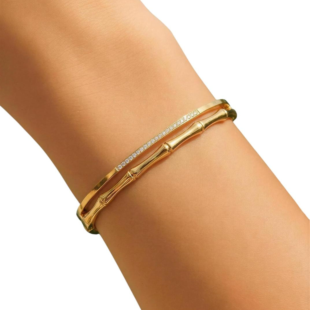 Gold bracelet with clear stones on a person's wrist against a white background