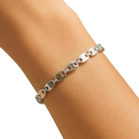Silver chain bracelet on a person's wrist against a white background