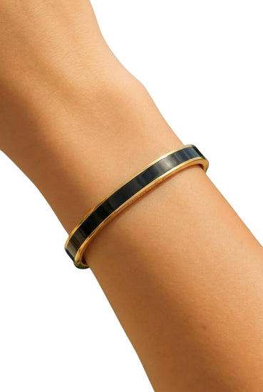 Gold and black bracelet on a wrist against a white background