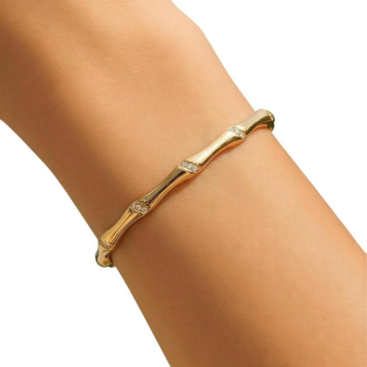 Gold bracelet with small diamonds on a wrist against a white background
