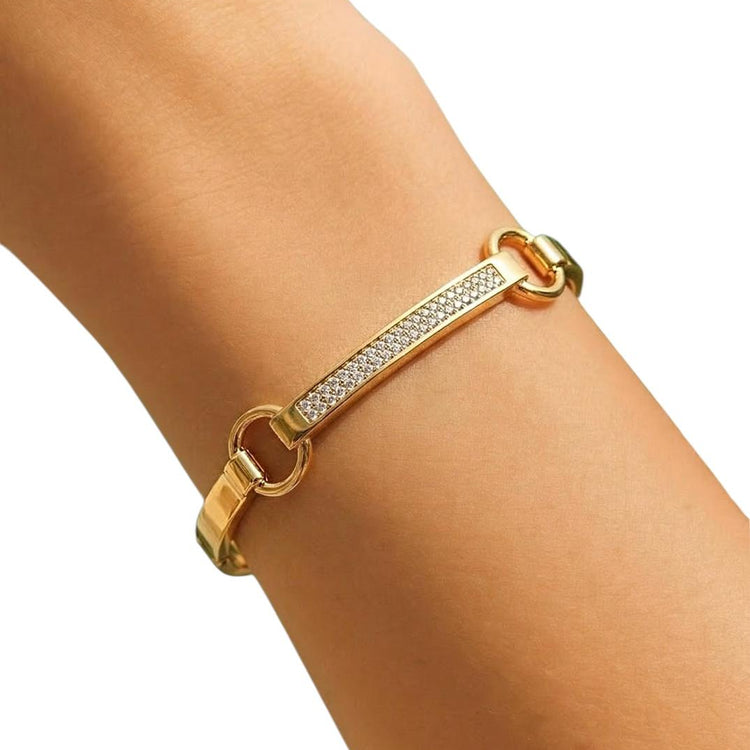 Gold bracelet with embedded stones on a wrist against a white background