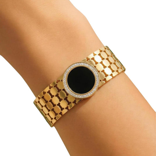 Gold bracelet with a black center on a wrist against a white background