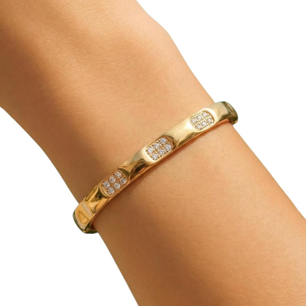 Gold bracelet with embedded stones on a wrist against a white background