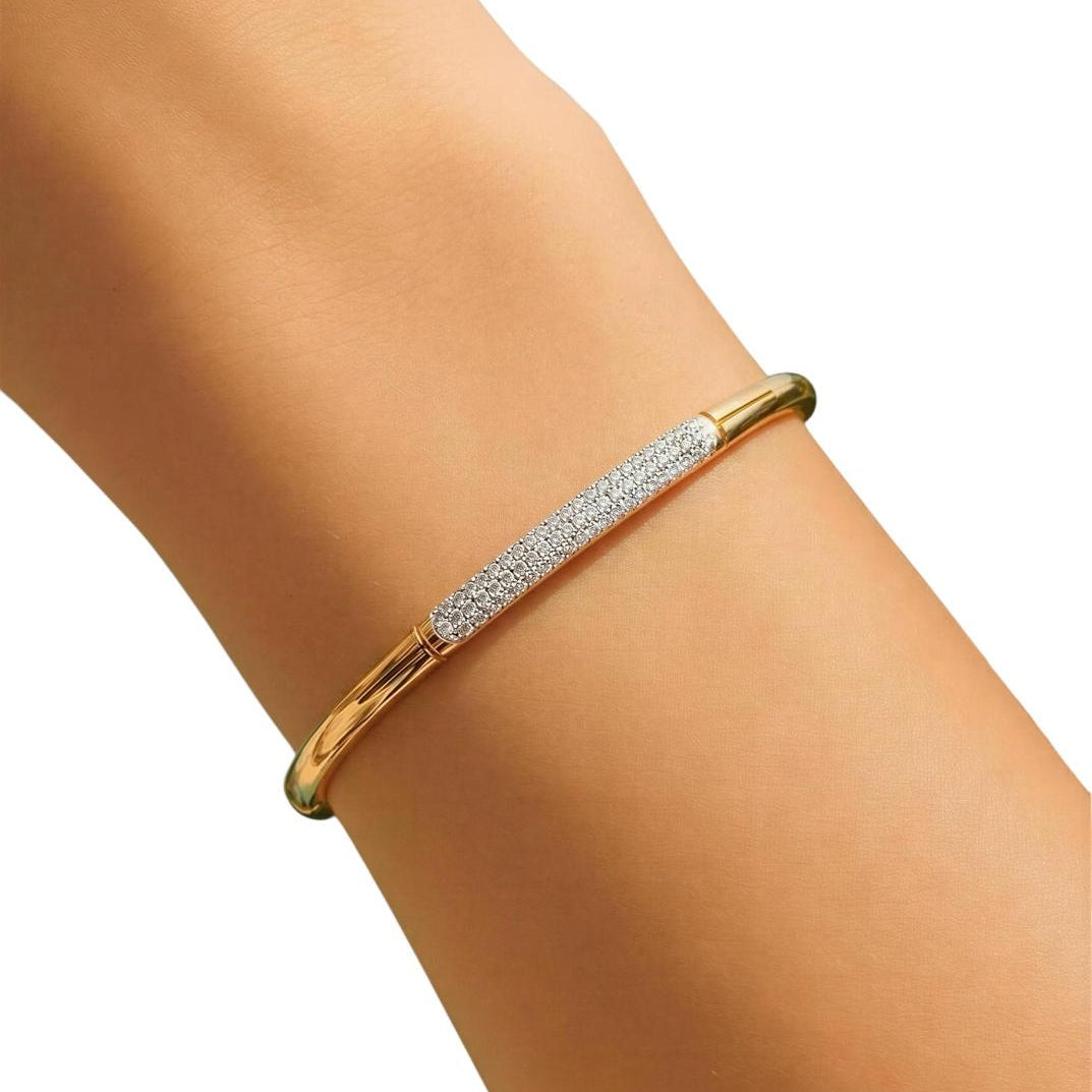 Gold bracelet with embedded stones on a wrist against a white background