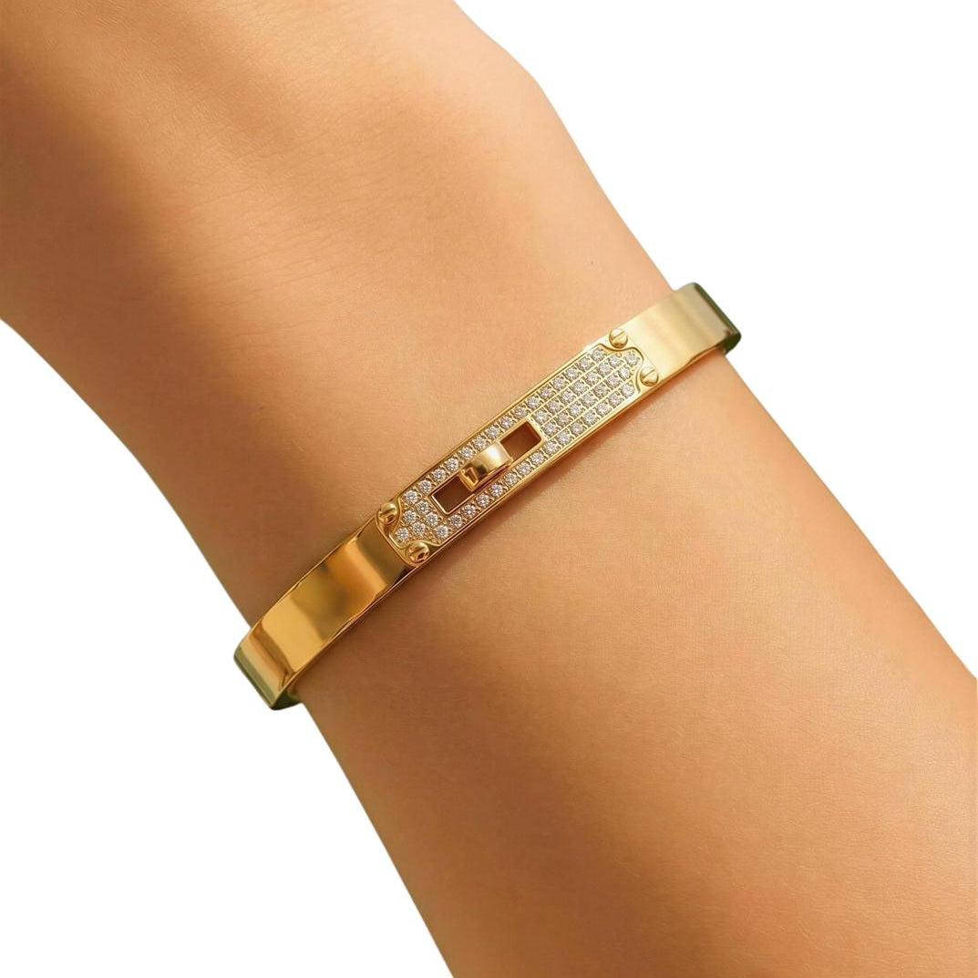 Gold bracelet with diamond accents on a wrist against a white background