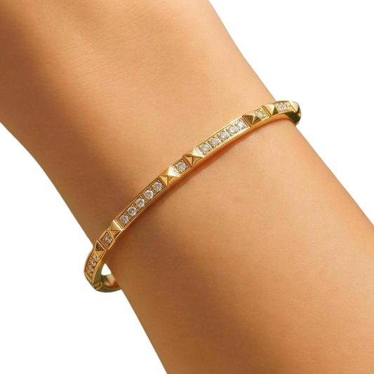 Gold bracelet with clear stones on a person's wrist against a white background