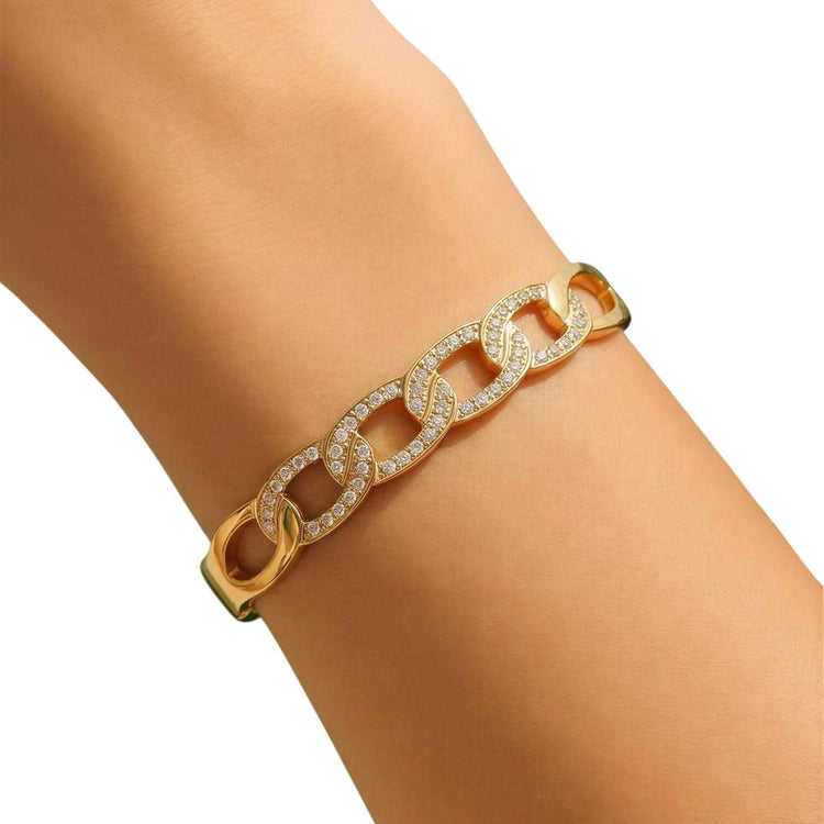 Gold chain bracelet with diamond accents on a wrist against a white background