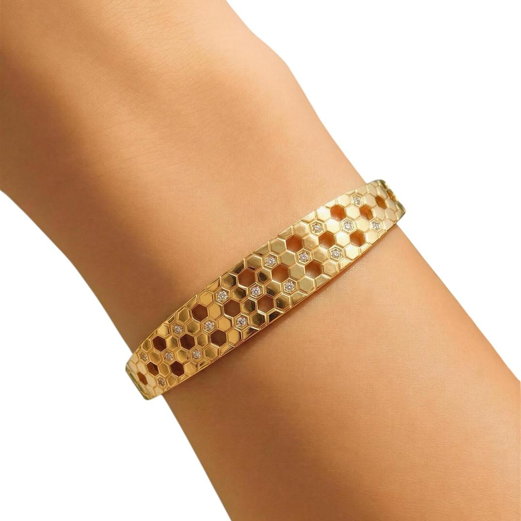 Gold bracelet on a wrist with a white background