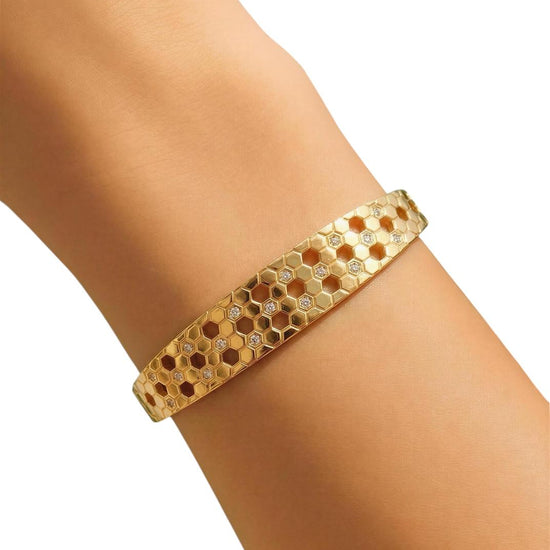 Gold bracelet on a wrist with a white background
