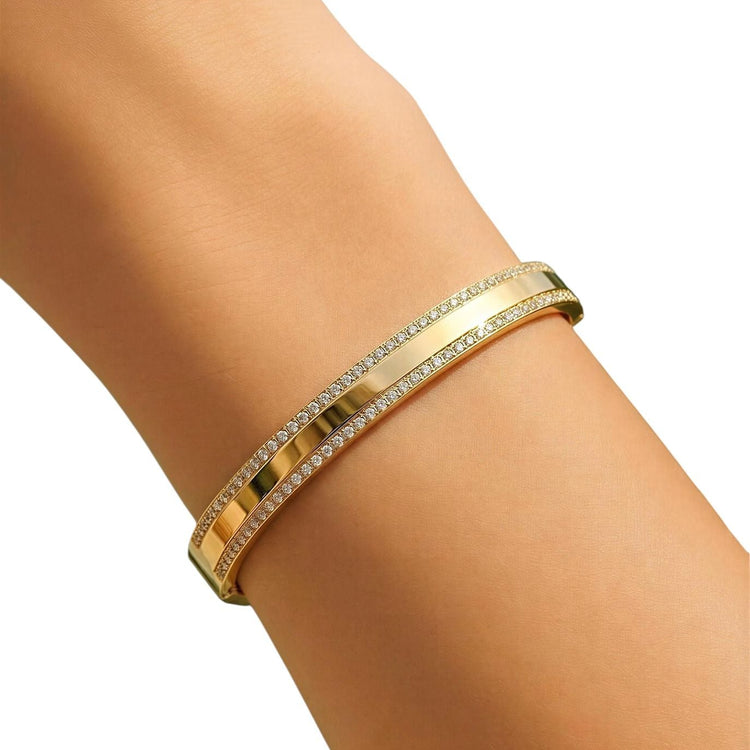 Gold bracelet with clear stones on a person's wrist against a white background